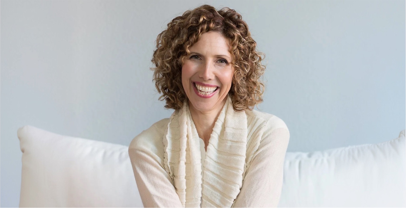 Regina Martinelli laughing on a white sofa